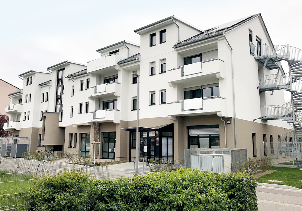 Gesamtansicht des sanierten Wohn-Geschäftshauses in Mannheim, Marienburger Str. 37-39, Ansicht des Kunden-Service-Centers der GBG Wohnen GmbH und rechts die Fluchttreppe am Giebel, fertiggestellt durch MACON BAU im Februar 2025