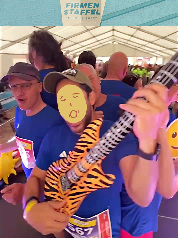 Mitarbeiter der MACON BAU GmbH Magdeburg auf dem Video-Rondell, links mit Brille und Base Cape der GF Ulrich Fliegner, im Vordergrund ein Mitarbeiter mit Deko-Gitarre, alle in blauen Laufshirts und Starternummern