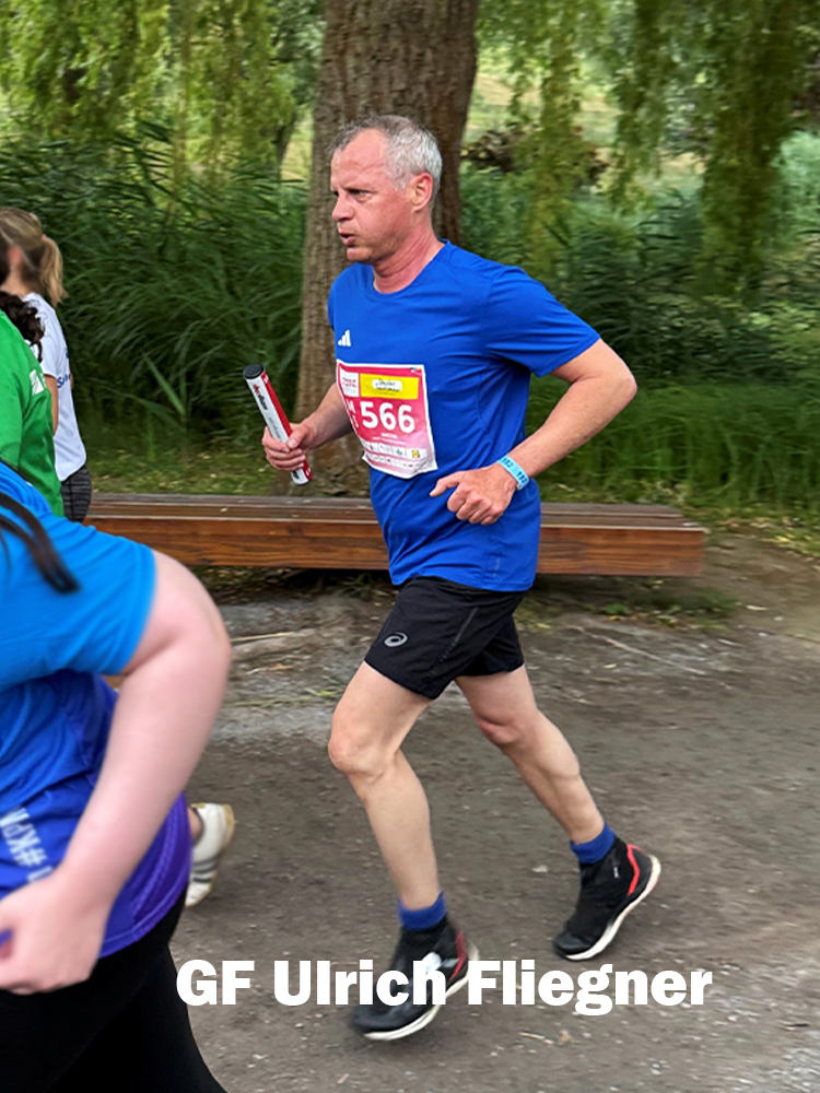 Der Geschäftsführer der MACON BAU GmbH Magdeburg beim Firmenlauf - mit blauem Shirt, Läufernummer 566 und Staffelstab in der Hand.