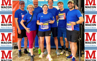 7 Staffelläufer der MACON BAU GmbH stehen vor dem Start in einheitlichen blauen Shirts und Sportkleidung beisammen